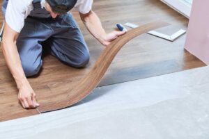 A person using a soft cloth and wood repair pen to fix a surface scratch on a hardwood floor.