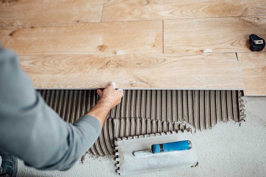 A person moving furniture and vacuuming an empty living room before floor installation.