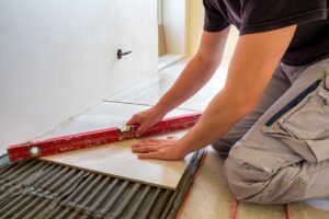 A person installing bamboo flooring over a subfloor in a residential living room.